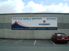 B�che publicitaire fix�e sur fa�ade d'une usine.